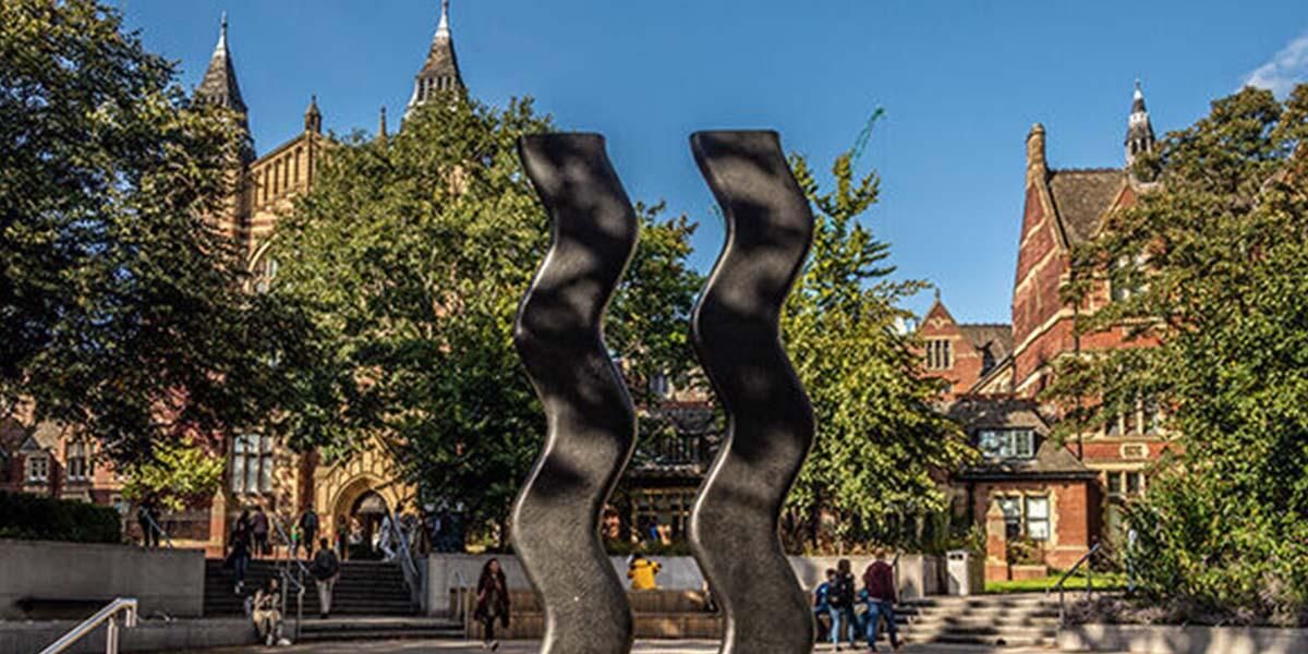 Students walking and sitting around the Sign for Art sculpture outside the Great Hall
