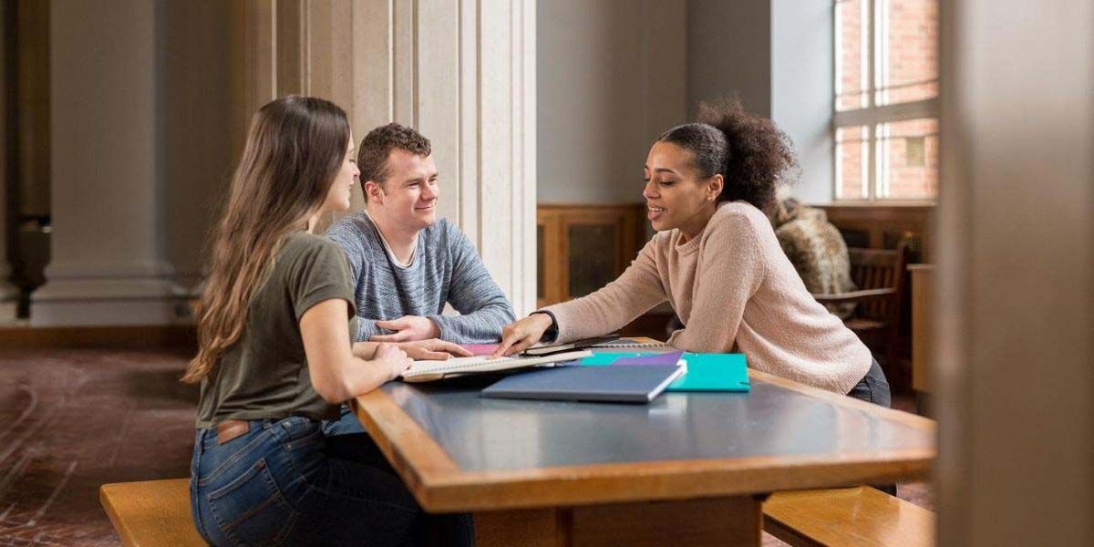 A group of students sat at a table in Parkinson Court, chatting and studying.