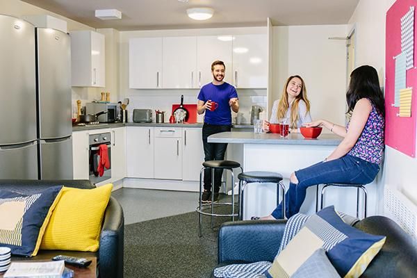 Three students chatting in the kitchen of their student accommodation