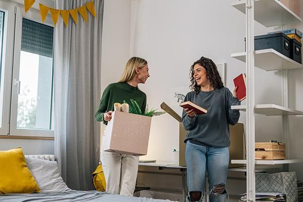 Two students packing items in a room into boxes