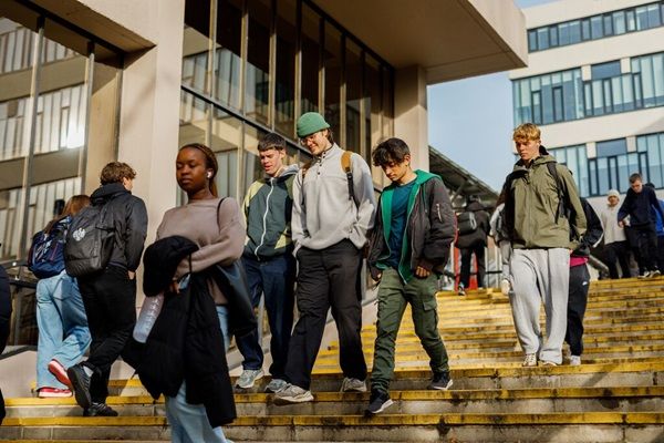 Students walking down a large set of steps on campus on a sunny day, with university buildings in the background.